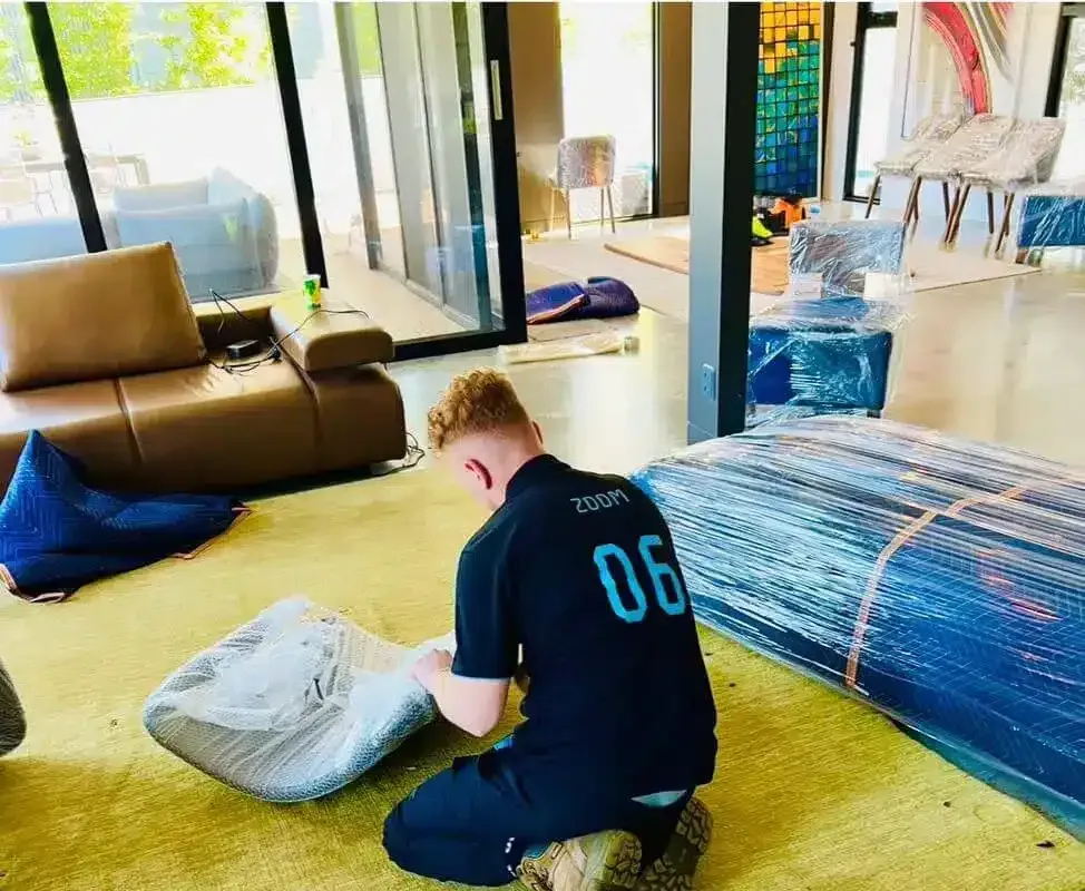 A 777 World Removals mover wrapping furniture for a house move in Shellharbour